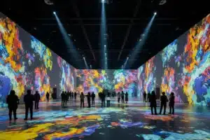 Salle d'exposition immersive à Paris avec projections colorées et visiteurs en silhouette