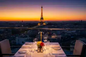 Restaurant avec vue Paris, table dressée en terrasse rooftop avec la Tour Eiffel illuminée au coucher du soleil