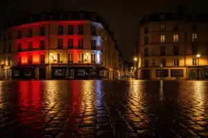 boite de nuit Paris ouverte, rue nocturne haussmannienne avec facades rouges et reflets sur paves