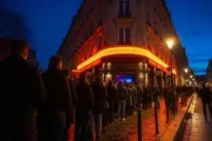 Entrée d'une boîte de nuit parisienne la nuit, file d'attente devant la façade illuminée