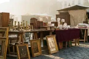 Étals d'un marché aux puces parisien avec chandelles en laiton et livres anciens sur pavés