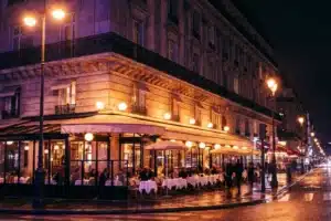 Terrasse d'une grande brasserie parisienne sur les Champs-Élysées le soir, tables dressées et lumières chaudes