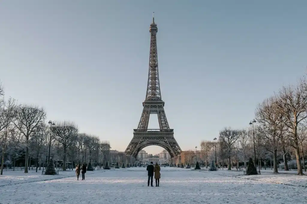 La tour Eiffel à Paris en hiver, pelouses enneigées et arbres dénudés givrés